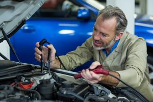 Mechanic testing a car battery with a voltmeter in an auto repair shop